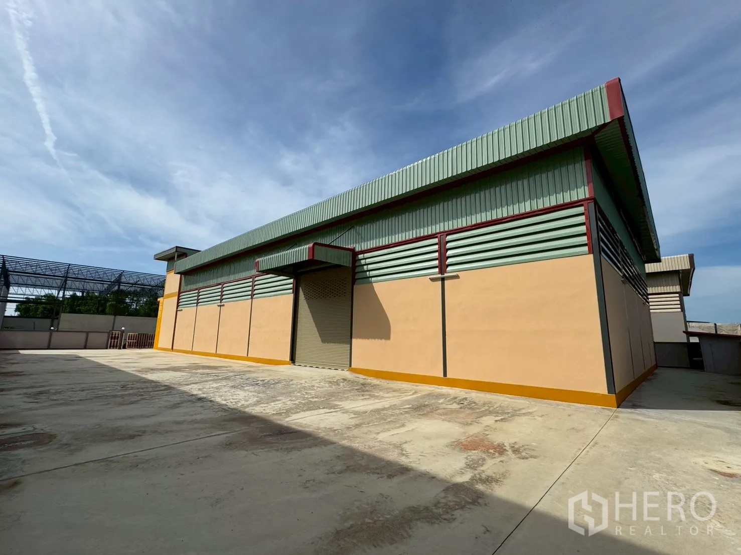 工厂 for sale in Mueang Samut Sakhon, Samut Sakhon - 仓库后侧金属板外墙与卷帘门，配大型硬化场地。