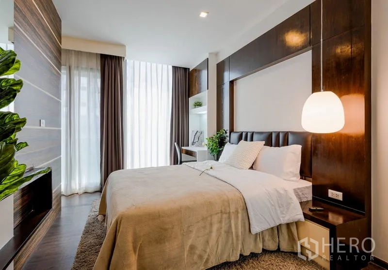 公寓 出售在Khlong Toei, Bangkok - 采光充足的主卧，宽大床铺、木质墙板、吊灯与落地窗帘，带书桌。