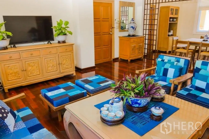 อพาร์ทเมนท์ ให้เช่าในPathum Wan, Bangkok - ห้องนั่งเล่นสว่างพร้อมตู้ทีวีไม้ โซฟาสีน้ำเงิน และพื้นไม้ขัดเงา ในอพาร์ตเมนต์ปทุมวัน