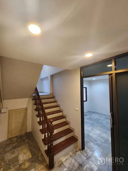 Townhouse for rent in Wang Thonglang, Bangkok - Staircase with wooden steps beside a glass-partitioned room.