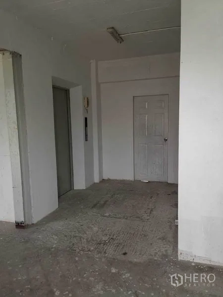 零售空间 出租在Watthana, Bangkok - 未完成的零售大厅，带电梯、白色墙面和水泥地面。