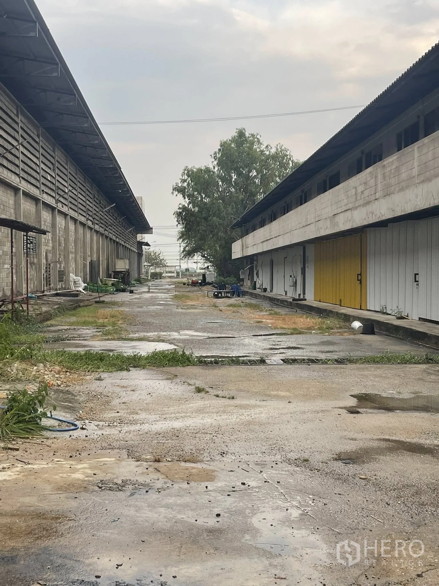 Factory for rent in Bang Bua Thong, Nonthaburi - Lane between two warehouse buildings with roller shutters and utility areas.