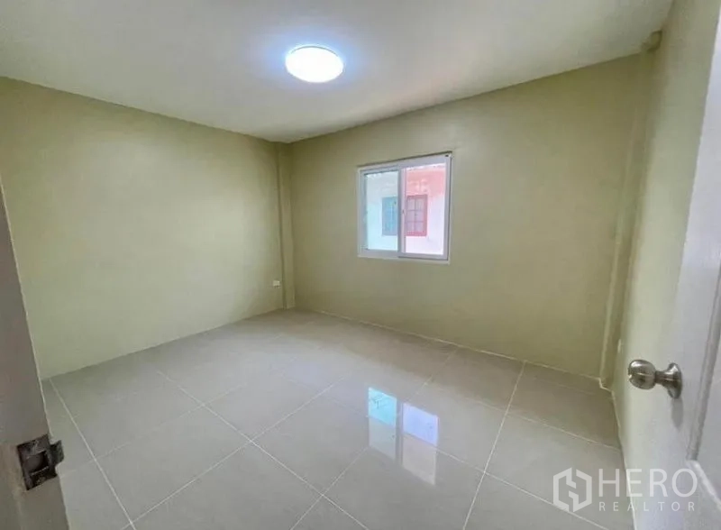 Townhouse for rent - Simple bedroom with window and ceiling light on polished tiles.