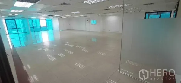 办公空间 出租在Huai Khwang, Bangkok - 开放式办公区，亮面瓷砖地面、格栅吊顶照明，玻璃隔断与蓝色镀膜窗，城市景观。