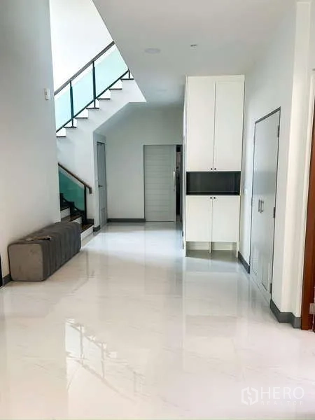 Detached House for rent in Bang Phli, Samut Prakan - Wide hallway with glossy tiles, built-in storage and staircase with glass balustrade.