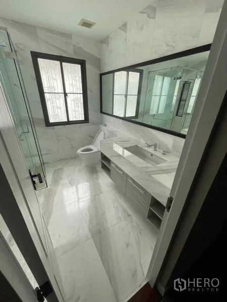 Detached House for sale in Mueang Samut Prakan, Samut Prakan - Contemporary bathroom with marble-look tiles, double sink and glass shower.