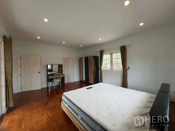 Detached House for rent in Bang Phli, Samut Prakan - Large bedroom showing wardrobe, vanity desk, wood floor, and bright windows.