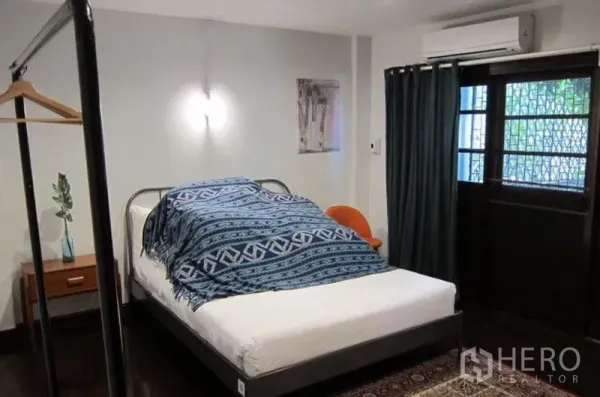 Townhouse for rent in Khlong Toei, Bangkok - Cozy bedroom with double bed, air conditioner, curtains and door with security grille.