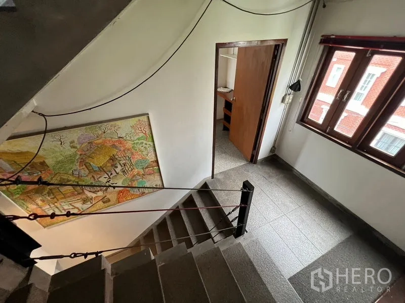 Office Space for rent in Watthana, Bangkok - Staircase landing with windows, wall artwork, and terrazzo flooring leading to the office level.