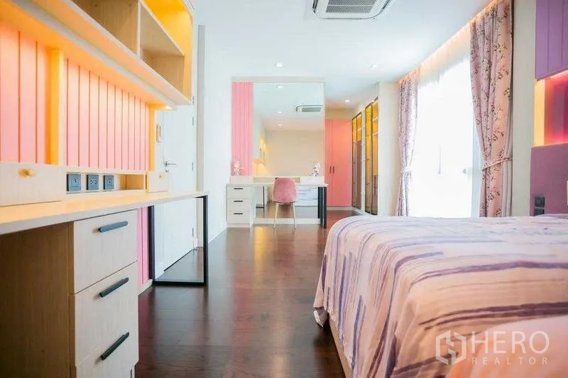 Detached House for rent in Bangkok - Bedroom view toward vanity and wardrobes with wood floors and pastel accents.