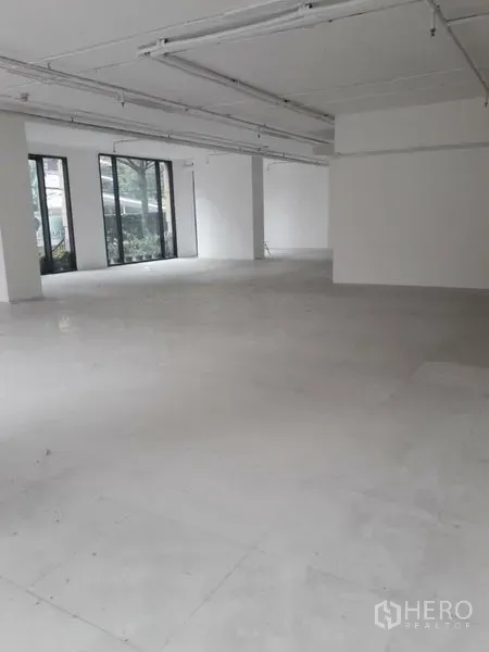 零售空间 出租在Watthana, Bangkok - 开放式零售室内，白色墙面、瓷砖地面，落地窗面向街道。