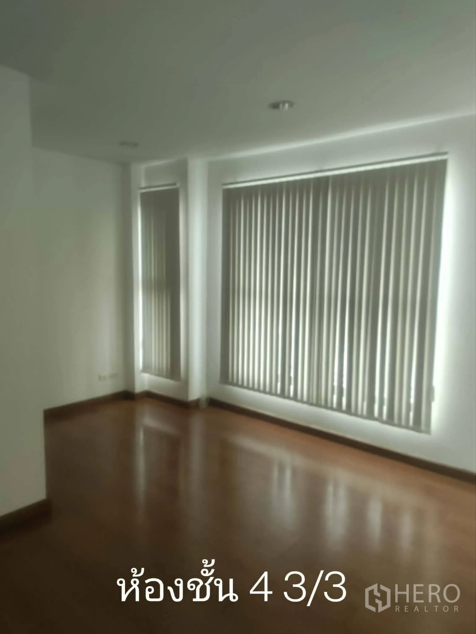 Home Office for rent in Lat Phrao, Bangkok - Bright empty room with wood flooring and vertical blinds on wide windows.