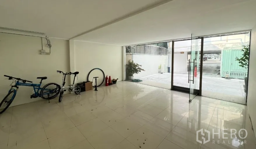 零售空间 出租在Watthana, Bangkok - 由室内望向入口的视角，亮面地砖与透明玻璃门。