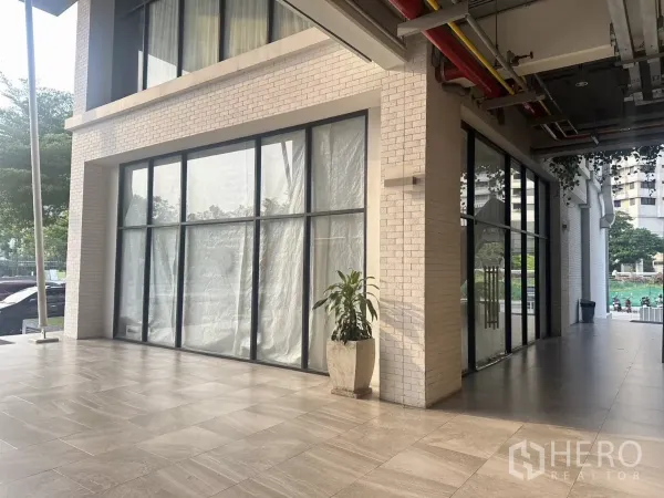 พื้นที่ขายปลีก ให้เช่าในKhlong Toei, Bangkok - หน้าร้านชั้นล่างตรงมุมอาคาร กระจกเต็มบาน ทางเดินมีหลังคาและลานกระเบื้องกว้าง