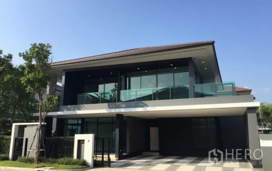 独立式住宅 出售在Bang Kapi, Bangkok - 华马克 Bang Kapi 现代两层独栋别墅，玻璃阳台、落地窗、带门禁入口与遮蔽车位，晴天外观。