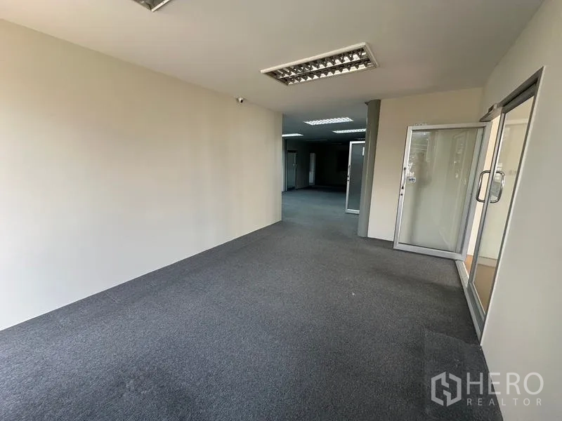 Office Space for rent - Carpeted corridor connecting glass-partitioned offices and meeting rooms.