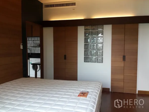 คอนโด ให้เช่าในWatthana, Bangkok - ห้องนอนพร้อมตู้เสื้อผ้าบิลท์อิน ผนังกระจกบล็อก และไฟซ่อนให้บรรยากาศอบอุ่น