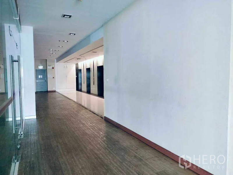 Office Space for rent in Sathon, Bangkok - Bright corridor and lift lobby finished with wood‑look flooring and a glass partition.
