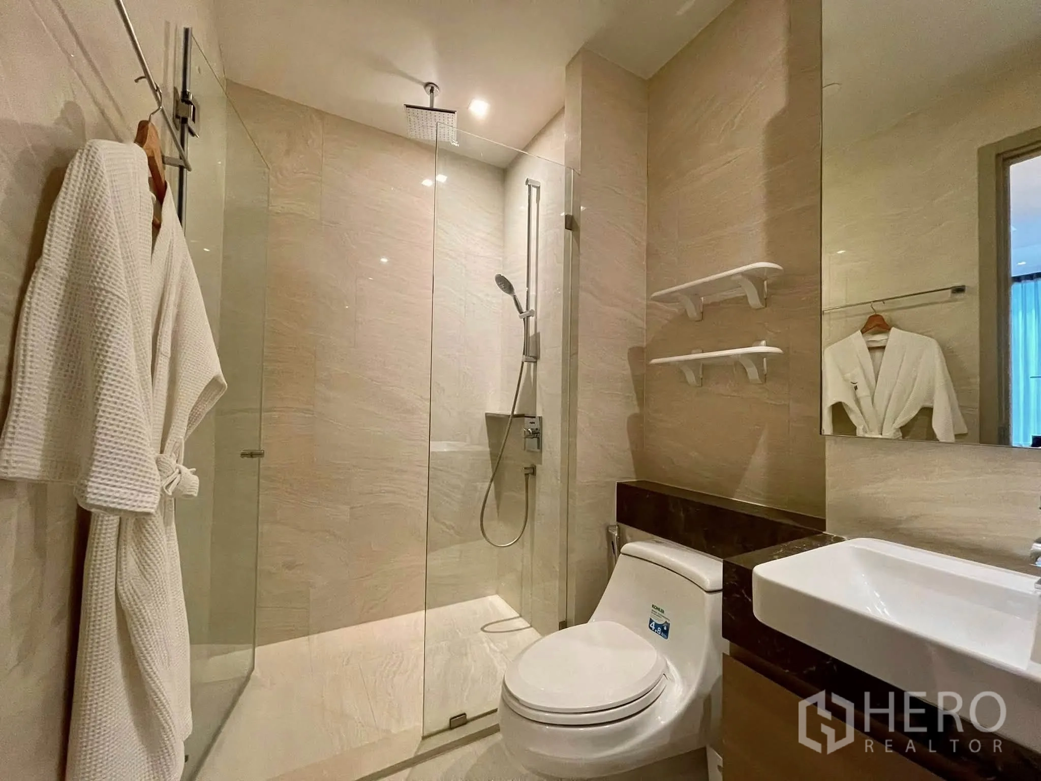Condominium for rent in Bang Rak, Bangkok - Bright bathroom with walk-in shower, vanity and wall shelves.