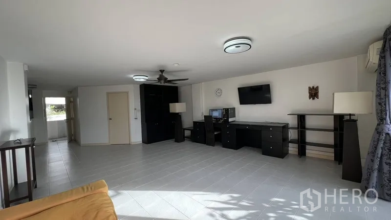 Condominium for sale in Wang Thonglang, Bangkok - Spacious living area with built-in desk, TV and large floor tiles.