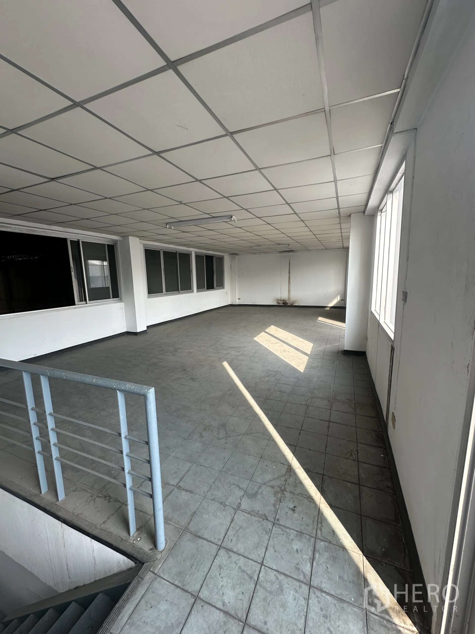 Factory for rent or sale in Khlong Luang, Pathum Thani - Open mezzanine level with stair railing, tiled floor and ceiling lights for flexible workspace.