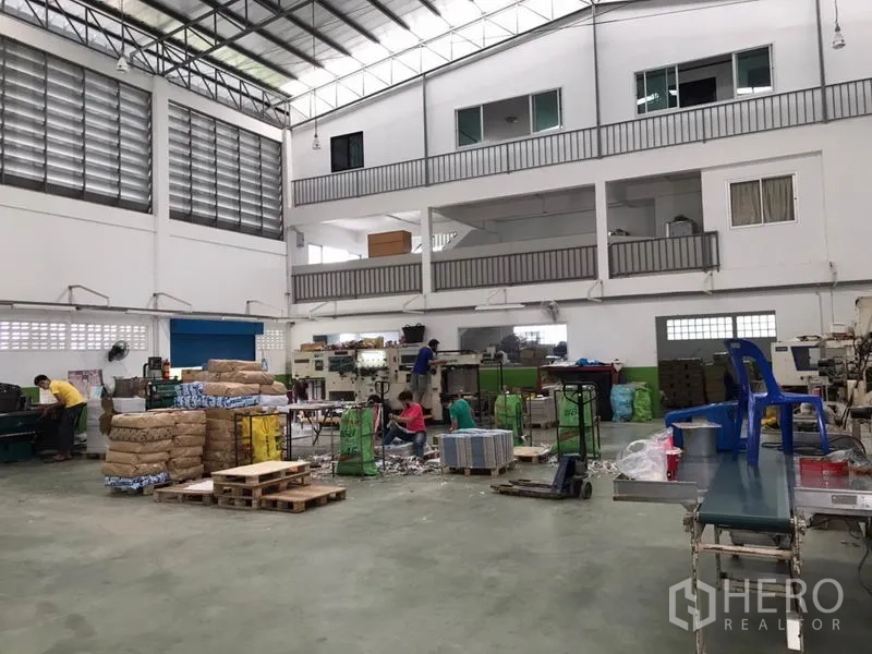 工厂 出售在Pak Kret, Nonthaburi - 宽阔车间地面，夹层、卷帘门与堆放材料
