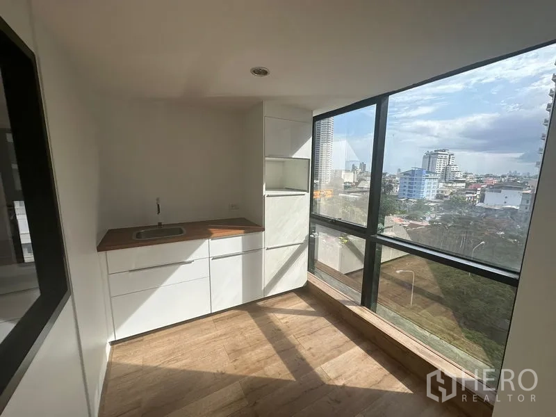 Office Space for rent in Sathon, Bangkok - Corner pantry with white cabinets, wood countertop, and wide city views through large windows in a bright Sathon office.