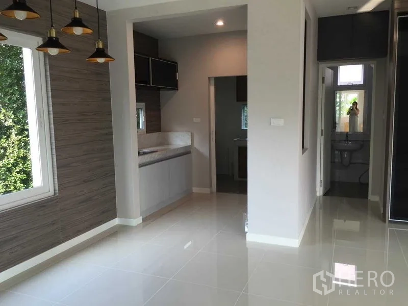 Townhouse for sale in Bang Khae, Bangkok - Open-plan dining area leading to a compact modern kitchen with pendant lights and tiled floors.