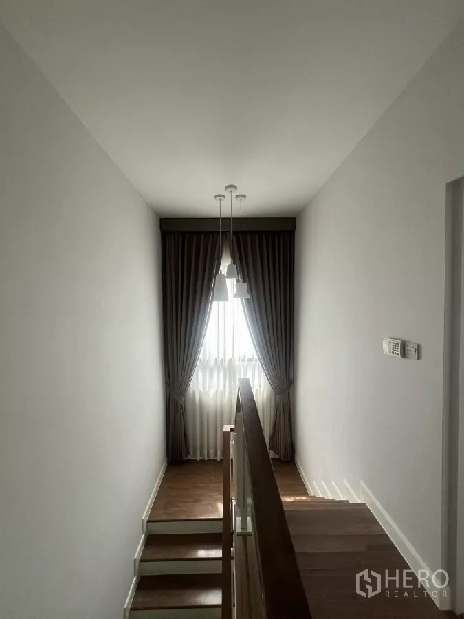 Detached House for sale in Bang Kapi, Bangkok - Staircase landing with pendant lights and a tall window dressed with drapes.
