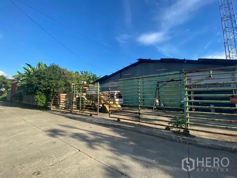 货栈 出租在Suan Luang, Bangkok - 仓库主立面与长金属大门，可见装卸场地与设备区。
