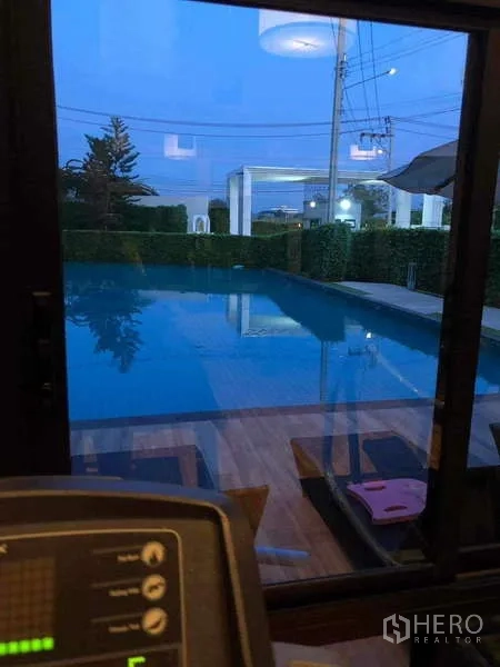 独立式住宅 出租或出售在Prawet, Bangkok - 透过落地窗看到社区泳池与健身区的夜景