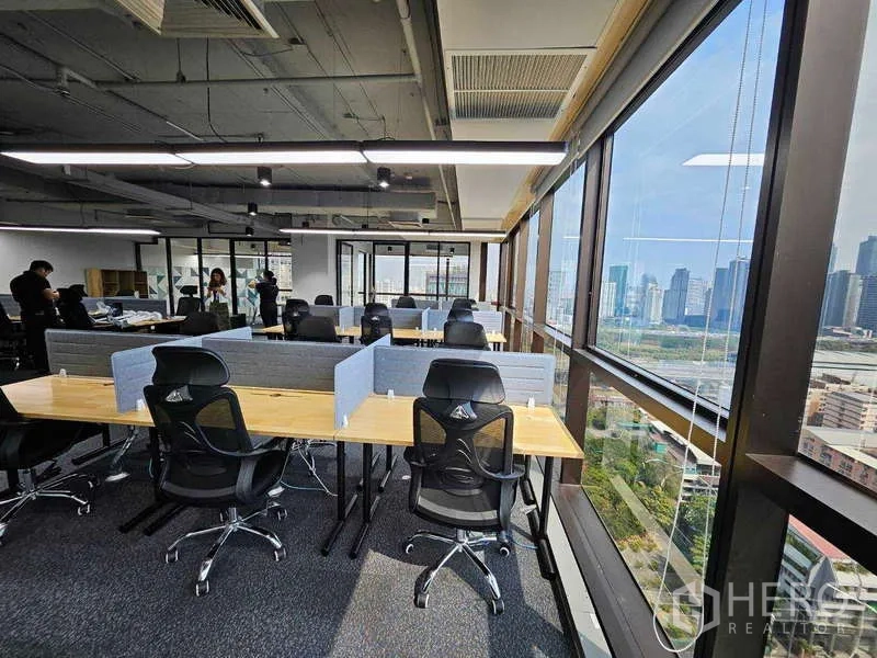 สำนักงาน ให้เช่าในRatchathewi, Bangkok - เก้าอี้ทำงานแบบอีร์โกโนมิกเรียงกับโต๊ะยาว เห็นวิวสกายไลน์กรุงเทพฯ จากกระจกโค้งรอบ