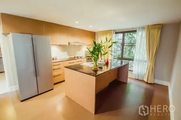 บ้าน ให้เช่าในKhlong Toei, Bangkok - ครัวสไตล์โมเดิร์นสว่าง ไอแลนด์ท็อปหินสีดำและตู้เย็นบานคู่ มองเห็นสวนผ่านหน้าต่าง.