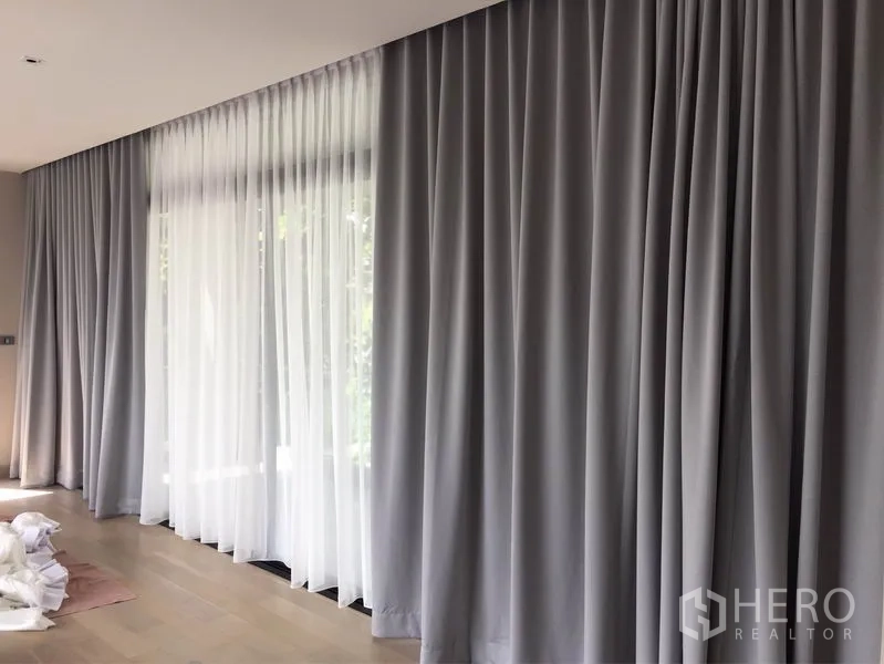 บ้าน ให้เช่าในWatthana, Bangkok - หน้าต่างยาวตลอดผนัง ติดผ้าม่านโปร่งสีขาวและม่านทึบสีเทา พื้นไม้