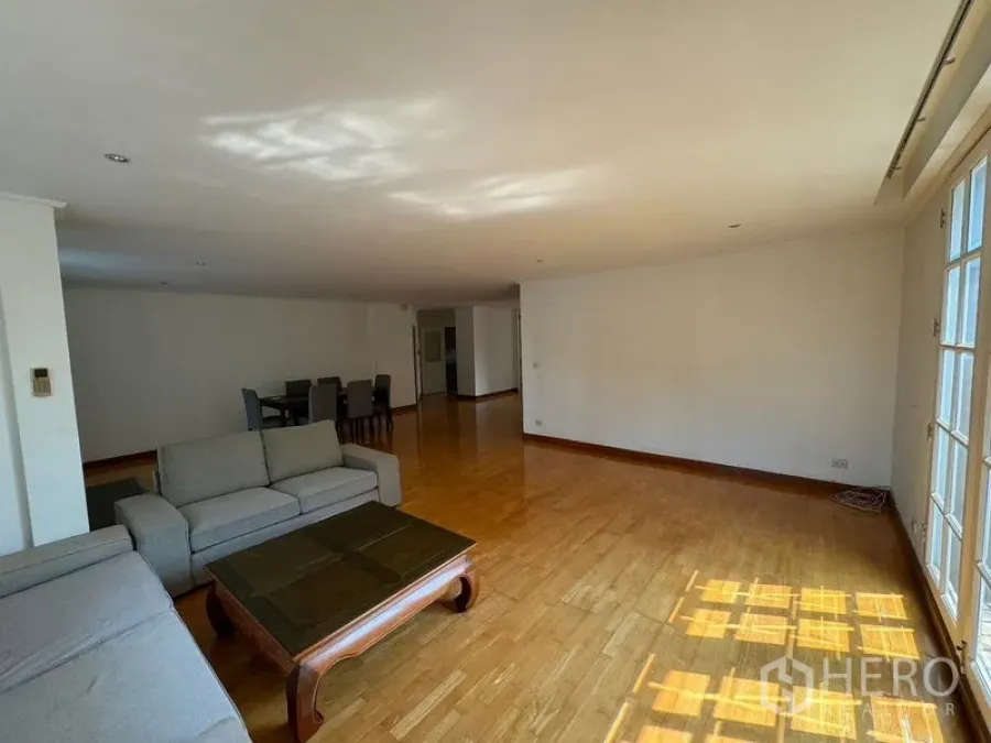 Condominium for rent in Yan Nawa, Bangkok - Open-plan living space with sofa set and dining area on wood floors.