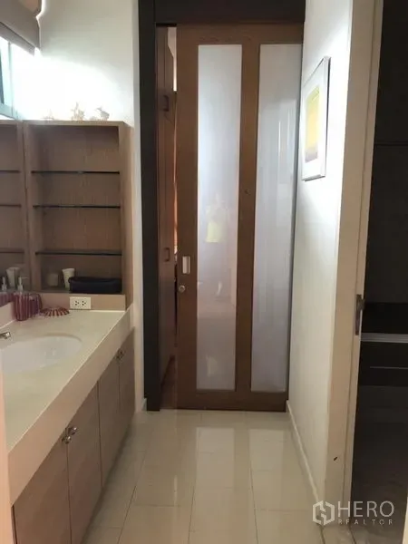 Condominium for rent in Bang Kho Laem, Bangkok - Modern bathroom with wide vanity, open shelving, and a frosted glass sliding door.