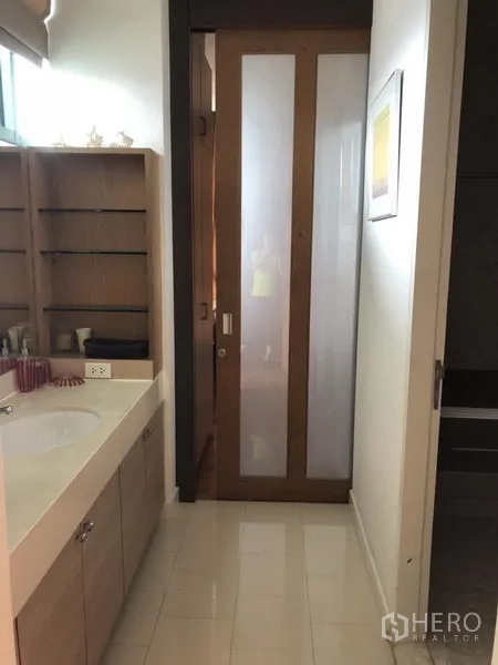 Condominium for rent in Bang Kho Laem, Bangkok - Modern bathroom with wide vanity, open shelving, and a frosted glass sliding door.