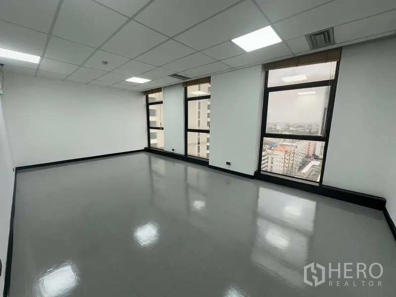 Office Space for rent - Large open office area with four tall windows and panoramic city outlook.