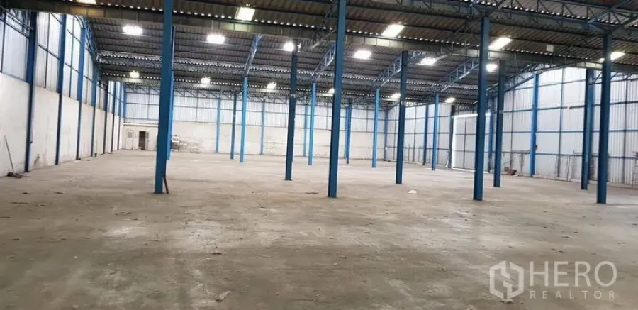 Warehouse for rent in Samut Prakan - Spacious warehouse interior with high steel columns, concrete floor and bright skylights.