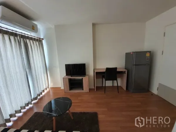 คอนโด ขายในChatuchak, Bangkok - โซนรับแขกมีผ้าม่านระเบียง ชั้นวางทีวี โต๊ะทำงาน และตู้เย็นในคอนโดกรุงเทพฯ