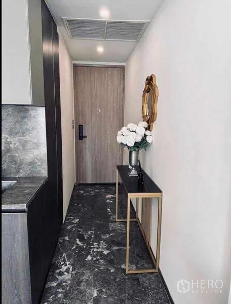Condominium for rent in Khlong Toei, Bangkok - Entrance hallway with console table, mirror and flowers.
