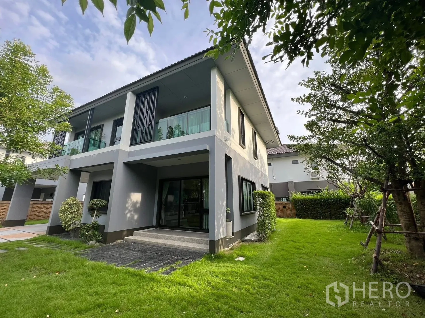 Detached House for rent in Bang Phli, Samut Prakan - Rear exterior of a modern two-storey house with covered terrace and landscaped lawn.