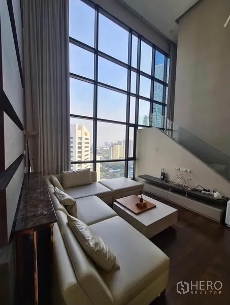 Condominium for rent or sale in Huai Khwang, Bangkok - Double-height living room with floor-to-ceiling windows and Bangkok city views.