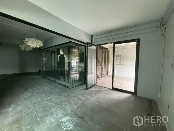 สำนักงาน ให้เช่า - โทนอุตสาหกรรม มีห้องกระจกกลางพื้นที่และประตูบานเลื่อนใกล้ทางเข้า.