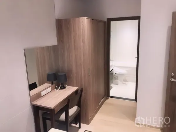 Condominium for rent or sale in Watthana, Bangkok - Compact dressing area with desk, mirror and wardrobe leading to a bright bathroom.