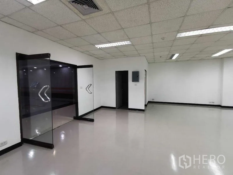 Office Space for rent in Watthana, Bangkok - Open-plan office interior with glass double doors, white walls and fluorescent ceiling lights.