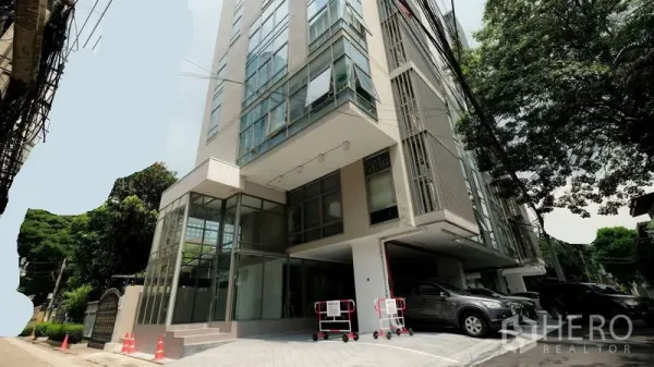 Office Space for rent in Bang Rak, Bangkok - Modern low-rise office building exterior with glass façade, driveway and parking amid trees in Silom.
