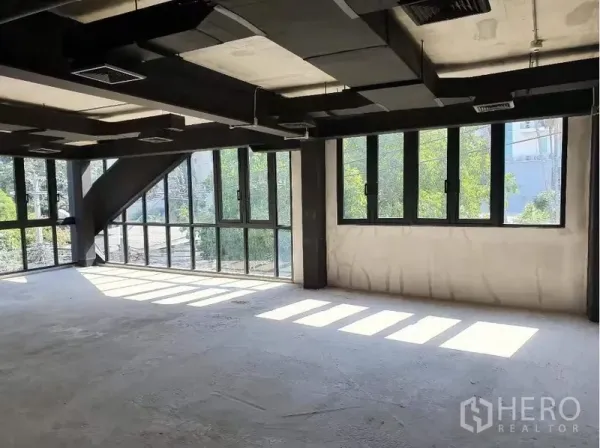 零售空间 出租在Khlong Toei, Bangkok - 明亮零售区域，成排可开启窗，黑色钢梁与水泥地面。