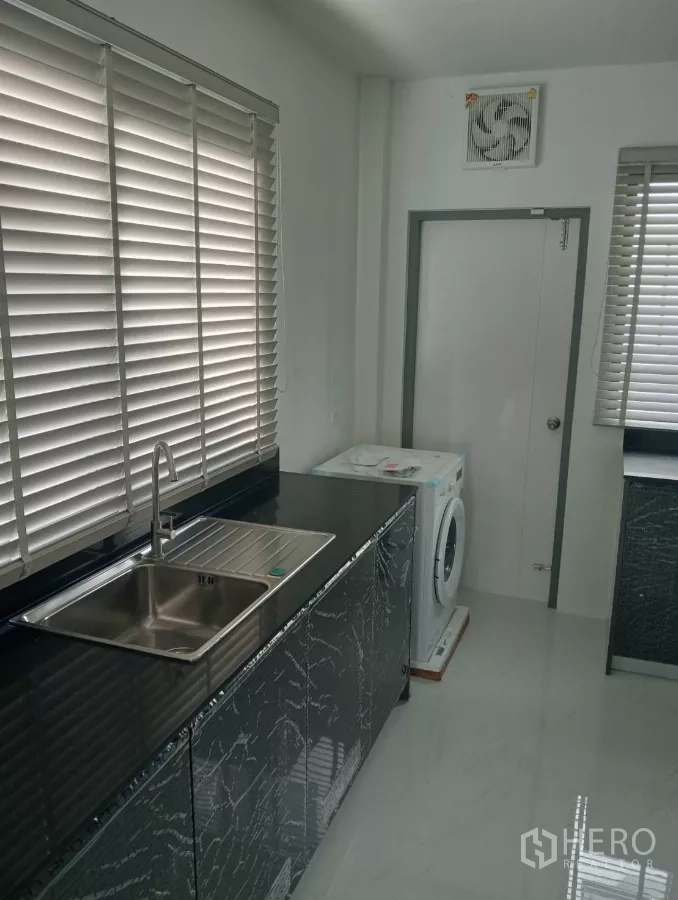 Detached House for rent in Bang Phli, Samut Prakan - Utility kitchen with stainless sink, countertop and washing machine by windows.