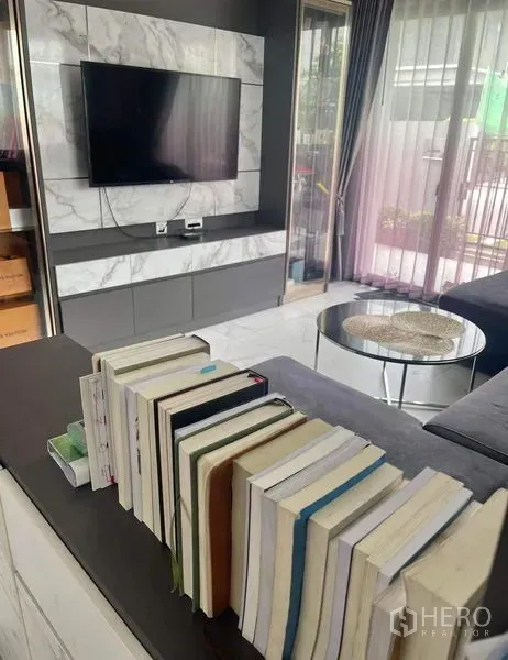 独立式住宅 出售在Bueng Kum, Bangkok - 明亮客厅，墙挂电视与大理石背景墙，推拉玻璃门通向花园。